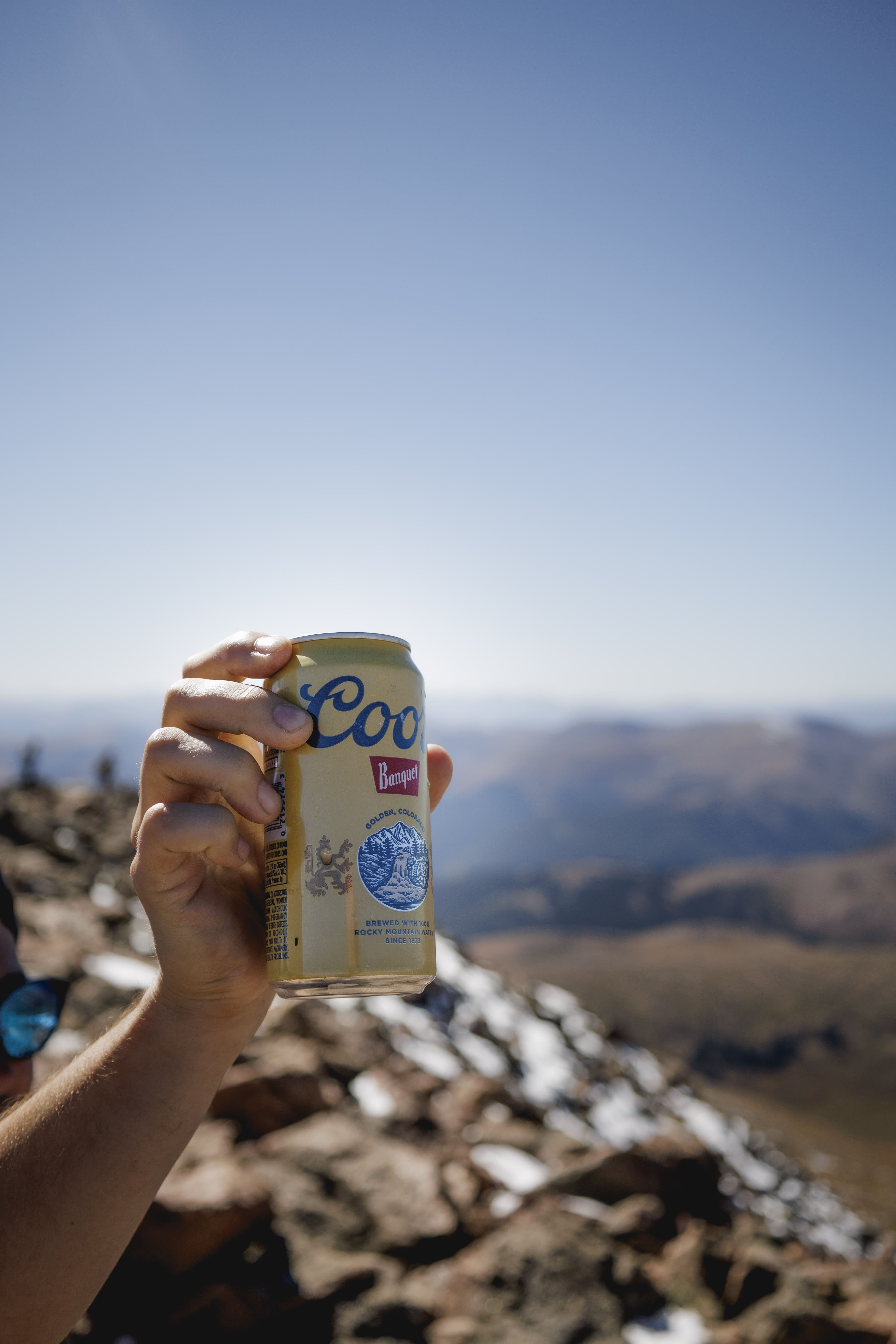 hand holding a can on top of a mountain