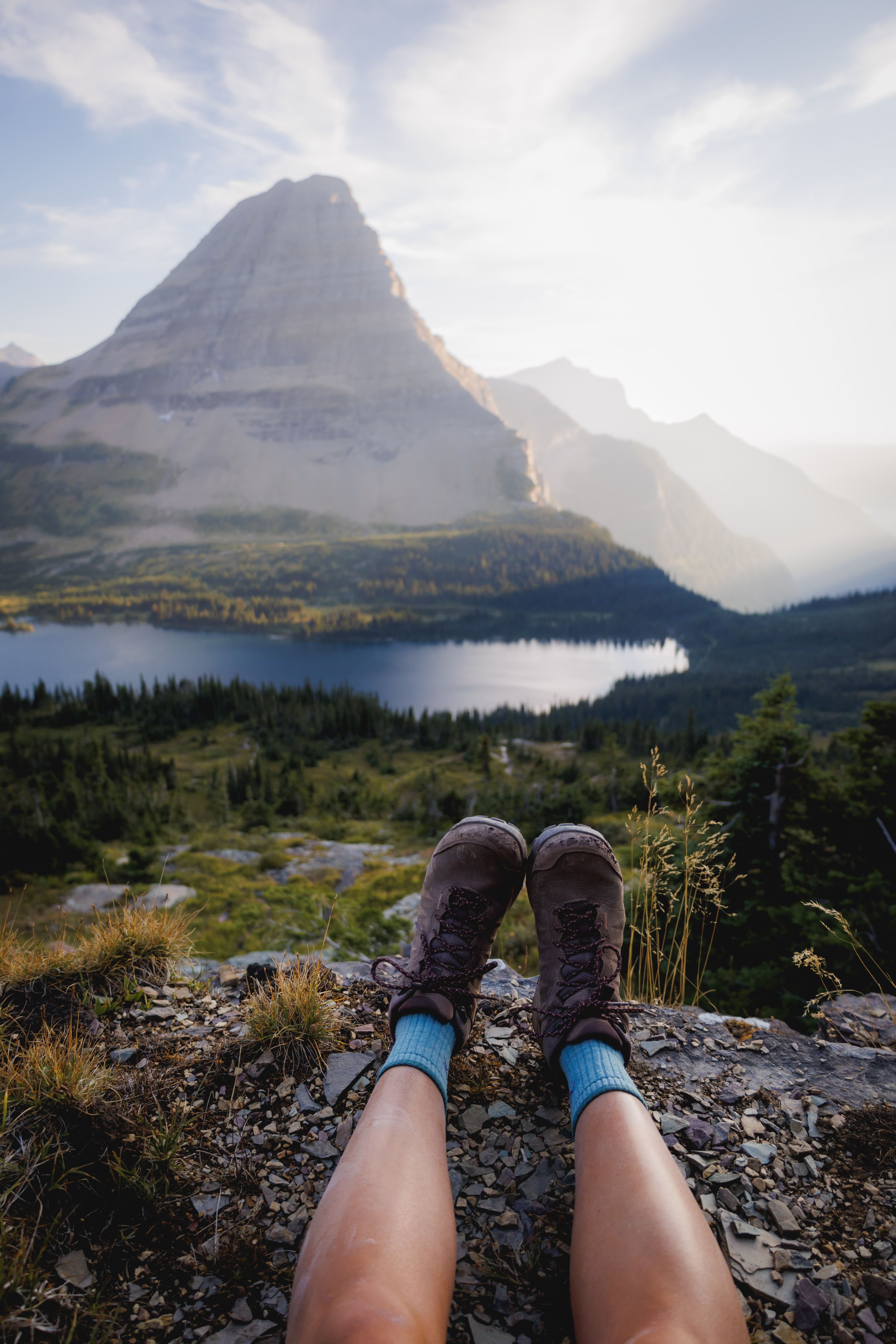 feet on a cliff in front of mountain