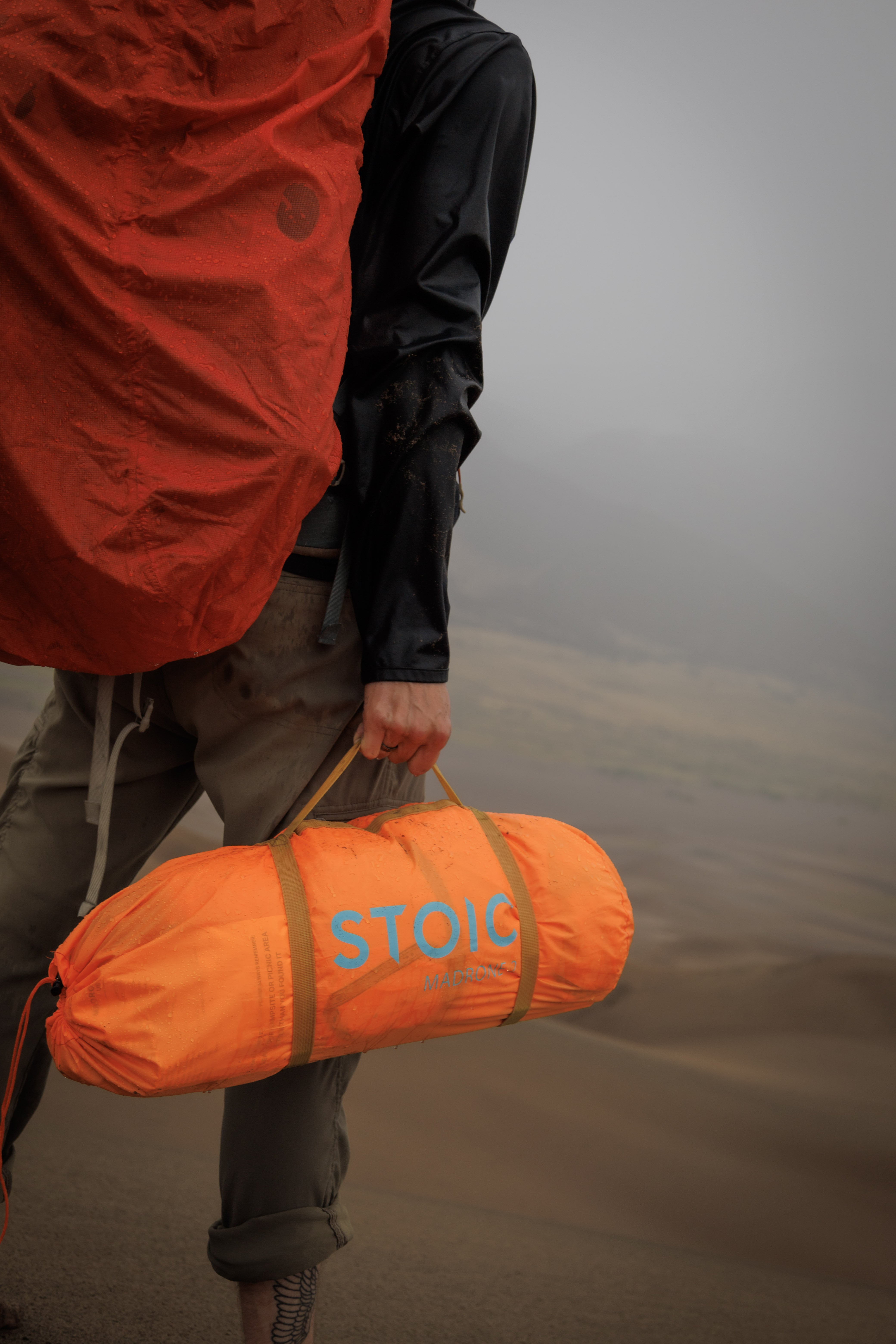 person holding an orange tent bag